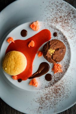 lezzetli tatlı tatlı üstten görünüm yuvarlak küçük pasta ve çikolata beyaz plaka üzerinde kırmızı vanilya sosu dekorasyonu ile