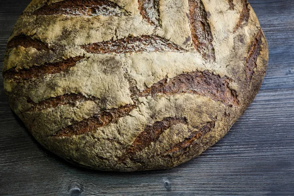 closeup büyük tamamen el yapımı yuvarlak siyah ekmek ile ilginç doku yalan üzerine koyu ahşap masa