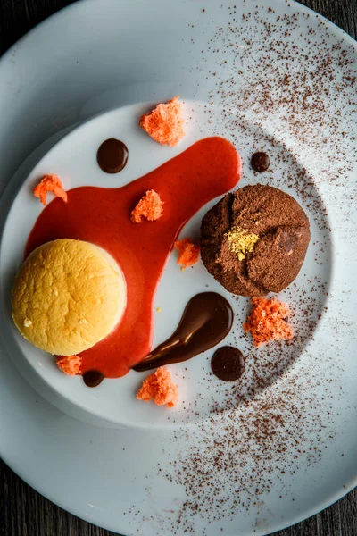 lezzetli tatlı tatlı üstten görünüm yuvarlak küçük pasta ve çikolata beyaz plaka üzerinde kırmızı vanilya sosu dekorasyonu ile