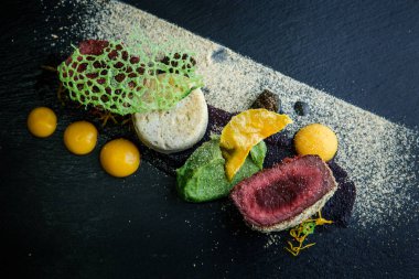 makro iki adet kavrulmuş et ile dekore edilmiş püresi ve siyah plaka restoran ahşap tablo üzerinde sos