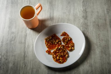 pembe fincan yeşil çay ve karamelize şeker tatlı olarak kabak çekirdeği ahşap masa arka plan üzerinde beyaz tabakta servis