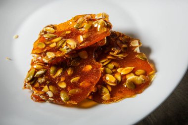 ahşap masa arka plan üzerinde beyaz tabakta servis karamelize şeker tatlı olarak makro kabak tohumu