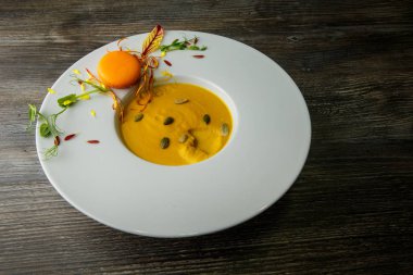 tohum ve turuncu acıbadem kurabiyesi dekorasyon ahşap arka plan üzerinde derin beyaz tabakta Taze kabak krem çorbası