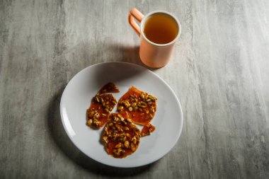 pembe fincan yeşil çay ve karamelize şeker tatlı olarak kabak çekirdeği ahşap masa arka plan üzerinde beyaz tabakta servis