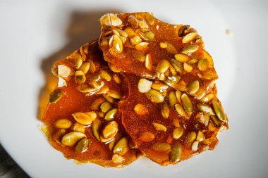 ahşap masa arka plan üzerinde beyaz tabakta servis karamelize şeker tatlı olarak makro kabak tohumu