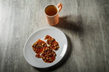 pembe fincan yeşil çay ve karamelize şeker tatlı olarak kabak çekirdeği ahşap masa arka plan üzerinde beyaz tabakta servis