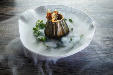 lezzetli tatlı taze nane ve ahşap masa arka plan üzerinde restoran plaka üzerinde duman süslenmiş kabak servis