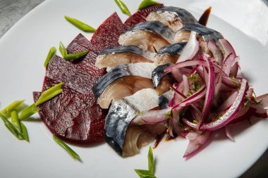 closeup uskumru ve pancar dilimleri gri masada beyaz Restoran tabakta servis doğranmış kırmızı ve yeşil soğan ile