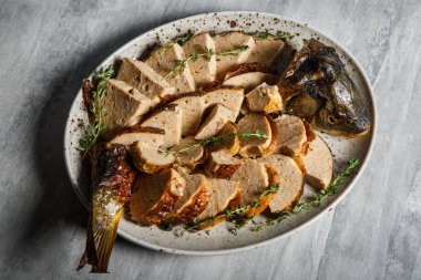 üstten görünüm beyaz Restoran plaka üzerinde otlar ile dekore edilmiş dilimlenmiş kavrulmuş doldurulmuş balık ile hizmet