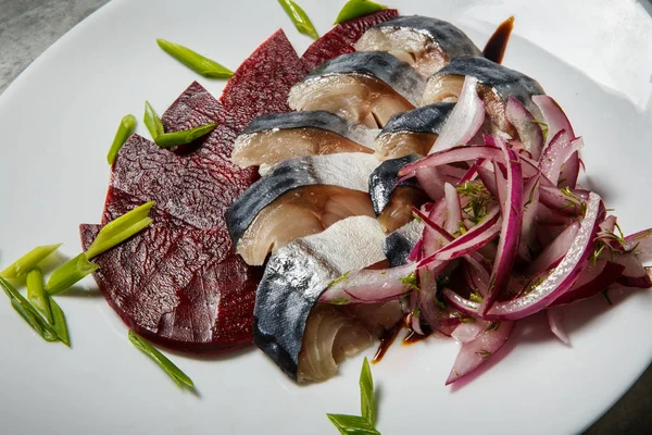 Closeup mackerel and beetroot slices with chopped red and green onion served on white restaurant plate on gray table — Stock Image Closeup Mackerel Beetroot Slices Chopped Red Green Onion Served White Royalty Free Stock Images