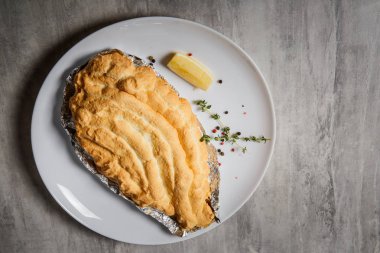 çırpılmış yumurta akı ile otlar ve limon gri masada beyaz Restoran tabakta servis folyo üzerinde altında pişmiş dorado üzerinde üstten görünüm