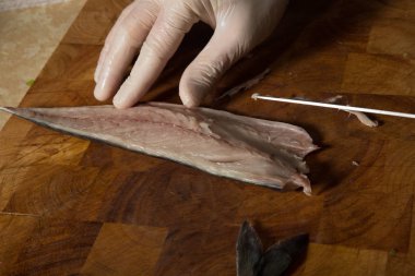 aşçı elinde eldiven hazırlamak ham uskumru fileto Ahşap Doğrama tahtası üzerinde bıçak ile