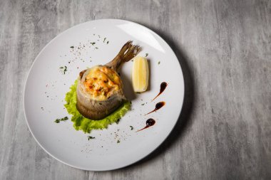 Fırında Alabalık peynir ve doldurma, somon salata, limon ve gri masada beyaz tabakta sos ile servis üzerinde üstten görünüm