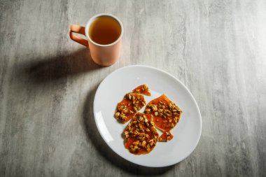 pembe fincan yeşil çay ve karamelize şeker tatlı olarak kabak çekirdeği ahşap masa arka plan üzerinde beyaz tabakta servis