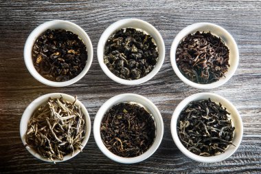 altı beyaz küçük yuvarlak gemiler çay yapraklarında ahşap masa arka plan üzerinde farklı türde üstten görünüm