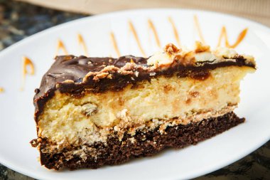 küçük parçası cheesecake ile çikolata karamel sulama ile beyaz plaka üzerinde yatıyor