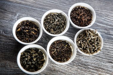 Karışık Meyveli tatlı çay yaprakları altı beyaz küçük damarları gri ahşap masa arka plan üzerinde yuvarlak