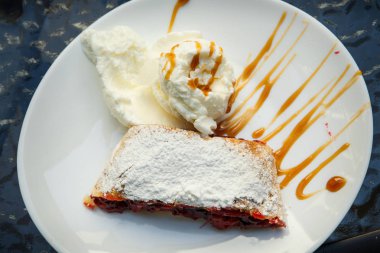 dondurma ve vişne strudel şeker tozu yalan karamel sulama ile dekore edilmiş beyaz tabakta süslenmiş üstten görünüm