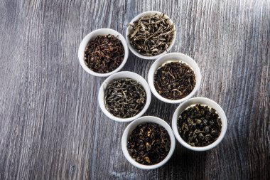 çeşitli çay altı beyaz küçük yuvarlak gemiler içinde gri ahşap masa arka plan üzerinde bırakır.