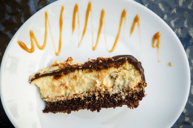 Yukarıdan küçük parçası cheesecake ile çikolata karamel sulama ile beyaz plaka üzerinde yatıyor