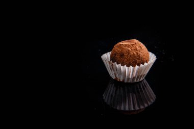 siyah ayna arka plan üzerinde kahverengi kakao tozu portre sağlıklı yararlı organik el yapımı yuvarlak çikolata şeker süslenmiş