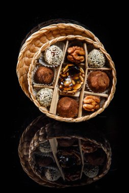 çeşitli sağlıklı yararlı el yapımı şekerlemeler ile dolu küçük el yapımı kutu dekore karamelize ayçiçeği ve kabak çekirdeği, kakao tozu, ceviz ve susam tohumu siyah ayna arka plan üzerinde