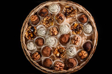 karamelize ayçiçeği ve kabak çekirdeği, kakao tozu, ceviz ve susam tohumu siyah arka plan üzerine dekore çeşitli sağlıklı yararlı el yapımı şekerlemeler ile dolu büyük bir el yapımı kutu üzerinde üstten görünüm