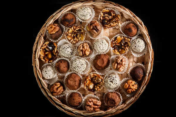 karamelize ayçiçeği ve kabak çekirdeği, kakao tozu, ceviz ve susam tohumu siyah arka plan üzerine dekore çeşitli sağlıklı yararlı el yapımı şekerlemeler ile dolu büyük bir el yapımı kutu üzerinde üstten görünüm