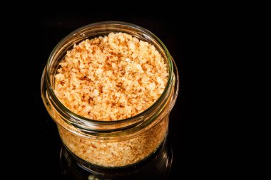 Üstten Görünüm küçük cam kavanoz büyük sarı doğal organik deniz tuzu ile siyah ayna arka plan üzerinde duruyor