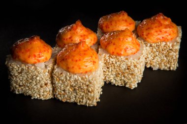 closeup pişmiş rulo ile somon, yeşil soğan, krem peynir dekore susam, peynir sos ve tobiko ile philadelphia havyar, üstte siyah arka plan üzerine hizmet