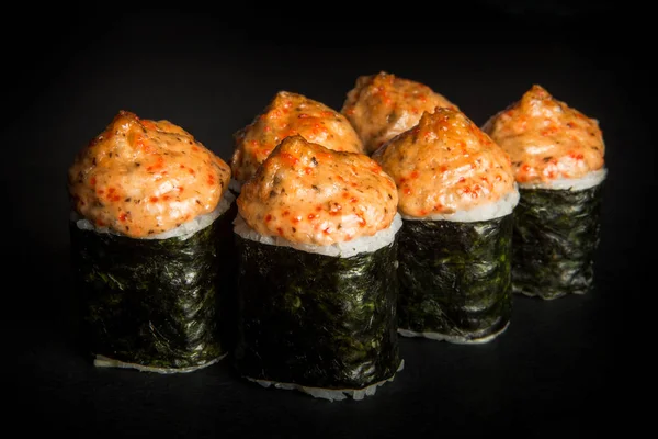 Closeup baked roll with mushrooms, tomatoes, philadelphia cream cheese decorated with nori, cheese sauce and tobiko caviar on top served on black background — Stock Image Closeup Baked Roll Mushrooms Tomatoes Philadelphia Cream Cheese Decorated Nori Stock Picture