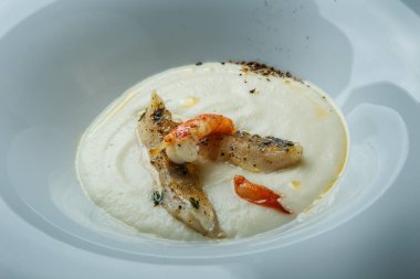 tatlı taze balık çorbası kızarmış adet balık, karides ve derin beyaz Restoran plaka üzerinde ahşap masa servis baharatlar ile süslenmiş krem