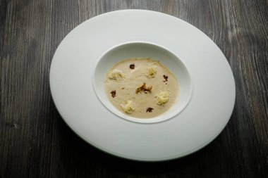 derin beyaz Restoran plaka ahşap masa üzerinde kurutulmuş kalamar ve soya sosu ile dekore edilmiş taze deniz ürünleri krem çorba servis