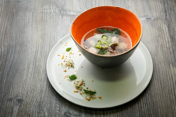 Delicious noodle soup with mushrooms, meat, and nettle leaves served in deep restaurant bowl on wooden table — Stock Image Delicious Noodle Soup Mushrooms Meat Nettle Leaves Served Deep Restaurant Stock Picture