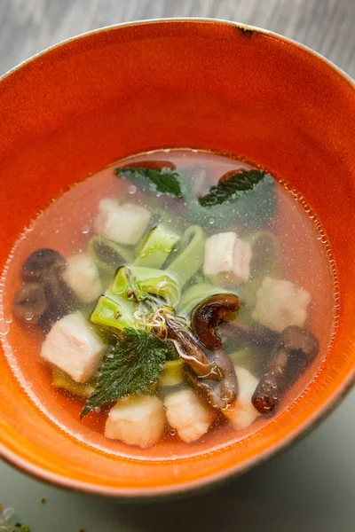Closeup noodle soup with mushrooms, meat, and nettle leaves served in deep restaurant bowl on wooden table — Stock Image Closeup Noodle Soup Mushrooms Meat Nettle Leaves Served Deep Restaurant Stock Photo