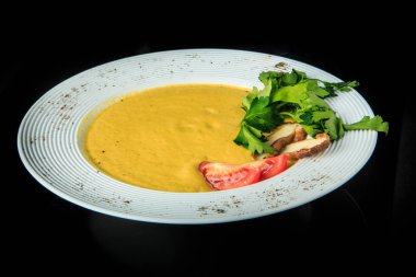 Sarı krem çorba dilimlenmiş mantar, domates ve yeşil maydanoz ile dekore edilmiş restoran derin beyaz tabak siyah arka plan üzerine hizmet bırakır