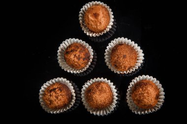 üstten görünüm sağlıklı yararlı organik el yapımı yuvarlak çikolata şekerleme büyük grup üzerinde siyah ayna arka plan üzerinde kahverengi kakao tozu ile dekore edilmiş