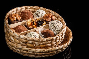 çeşitli sağlıklı yararlı el yapımı şekerlemeler ile dolu küçük el yapımı kutu dekore karamelize ayçiçeği ve kabak çekirdeği, kakao tozu, ceviz ve susam tohumu siyah ayna arka plan üzerinde