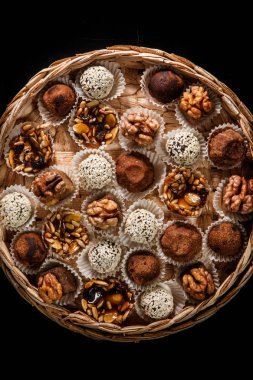 karamelize ayçiçeği ve kabak çekirdeği, kakao tozu, ceviz ve susam tohumu siyah arka plan üzerine dekore çeşitli sağlıklı yararlı el yapımı şekerlemeler ile dolu büyük bir el yapımı kutu üzerinde üstten görünüm