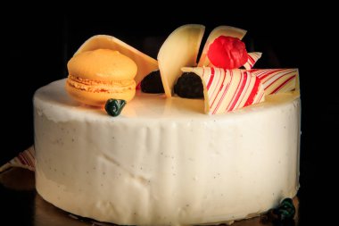 closeup lezzetli yuvarlak kek çikolata renkli, sarı acıbadem kurabiyesi ile dekore edilmiş beyaz sır ve siyah arka plan üzerine hizmet marmelat