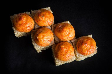 en çok pişmiş rulo somon, yeşil soğan, philadelphia krem peynir ile dekore edilmiş susam ile görünüm, peynir sosu ve siyah arka plan üzerine hizmet üstte tobiko havyar