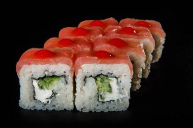 Japon Suşi orkinos, salatalık ve Philadelphia krem peynir kırmızı sos siyah arka plan üzerine hizmet süslenmiş ile rulo