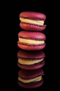 kule iki mor berry macaroons sarı dolgulu siyah ayna arka plan yansıması ile görev yaptı.