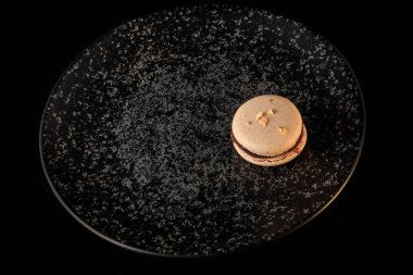 tek fıstık acıbadem kurabiyesi çikolata dolgulu siyah arka plan üzerine siyah dokulu tabakta servis