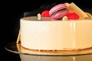 closeup lezzetli yuvarlak kek çikolata renkli, mor acıbadem kurabiyesi ile dekore edilmiş beyaz sır ve siyah arka plan üzerine hizmet marmelat