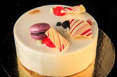 closeup lezzetli yuvarlak kek çikolata renkli, mor acıbadem kurabiyesi ile dekore edilmiş beyaz sır ve siyah arka plan üzerine hizmet marmelat