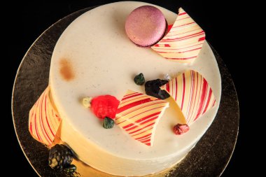 closeup lezzetli yuvarlak kek çikolata renkli, mor acıbadem kurabiyesi ile dekore edilmiş beyaz sır ve siyah arka plan üzerine hizmet marmelat