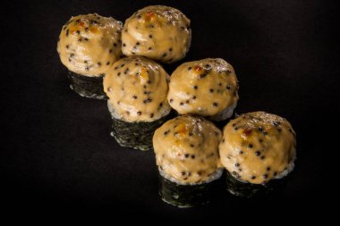 üstten görünüm portre rulo ile somon füme, salatalık, siyah arka plan üzerine hizmet peynir sos ile dekore edilmiş philadelphia krem peynir pişmiş