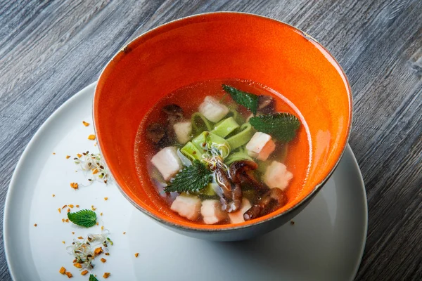 Top view tasty noodle soup with mushrooms, meat, and nettle leaves served in deep restaurant bowl on wooden table — Stock Image Top View Tasty Noodle Soup Mushrooms Meat Nettle Leaves Served Stock Picture