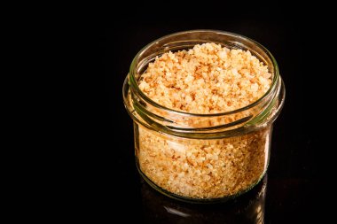 üstten görünüm portre küçük cam kavanoz büyük sarı doğal organik deniz tuzu ile siyah ayna arka plan üzerinde duruyor